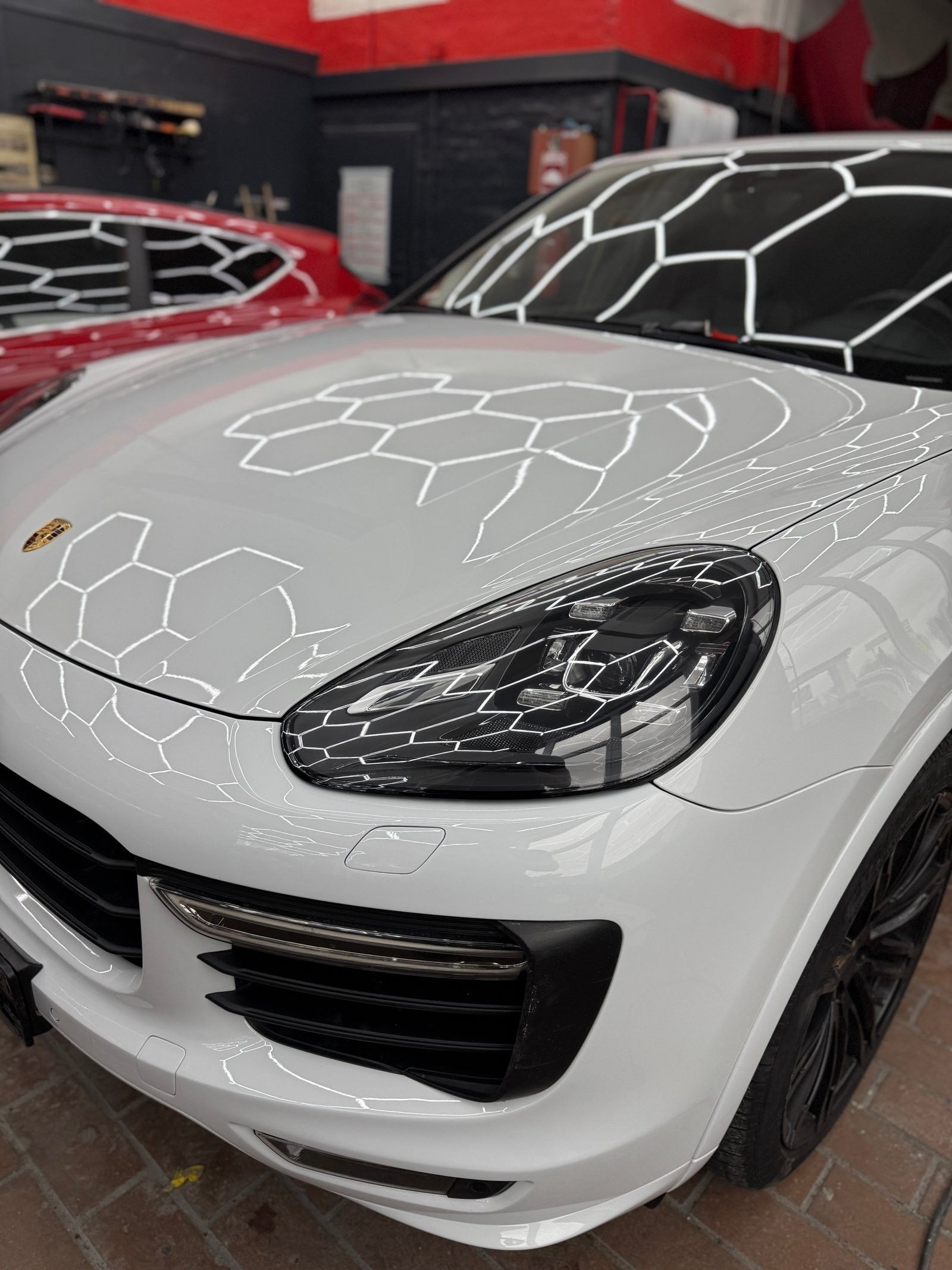 Weißer Porsche Cayenne unter der Hexagon-LED-Decke der Werkstatt von RC Smart Repair in Solingen